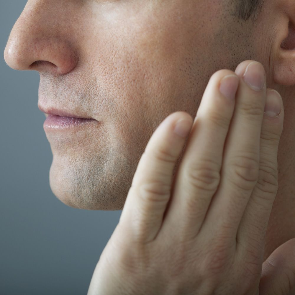 Man touching side of face